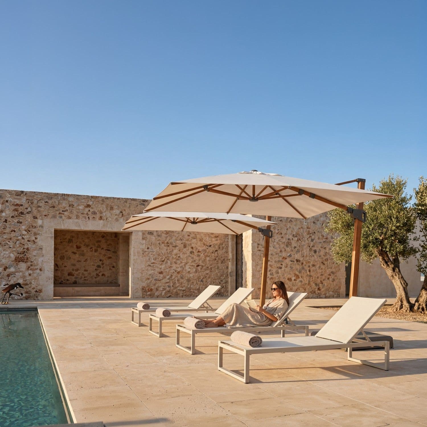 BLOOM Prestige luxury sun loungers & premium cantilever umbrellas by a stunning poolside terrace. Designer outdoor living for