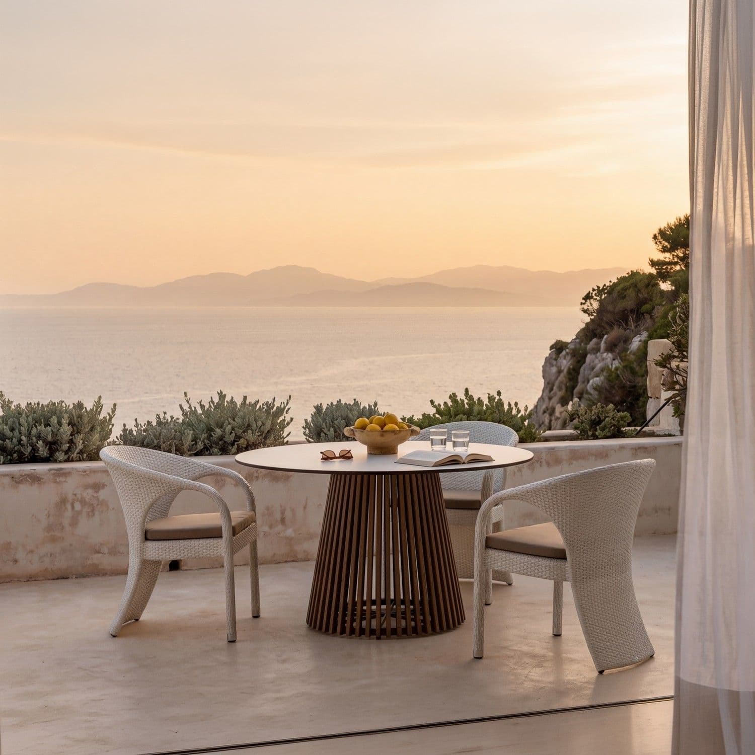 BLOOM Tuxedo luxury dining set: handcrafted woven chairs & premium table on a serene coastal terrace with stunning sea view.