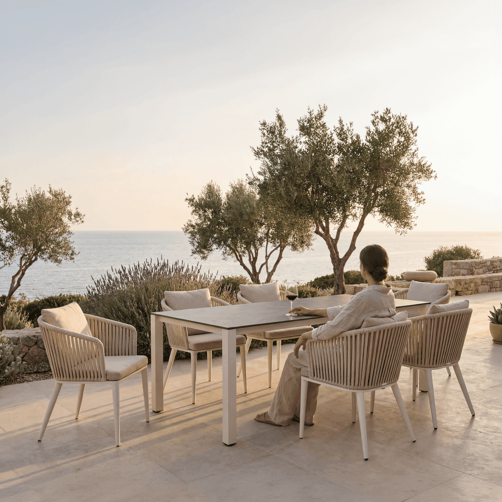Six Avalon outdoor dining chairs with woven rope and cushions around an aluminum-frame table on a Mediterranean sea-view.