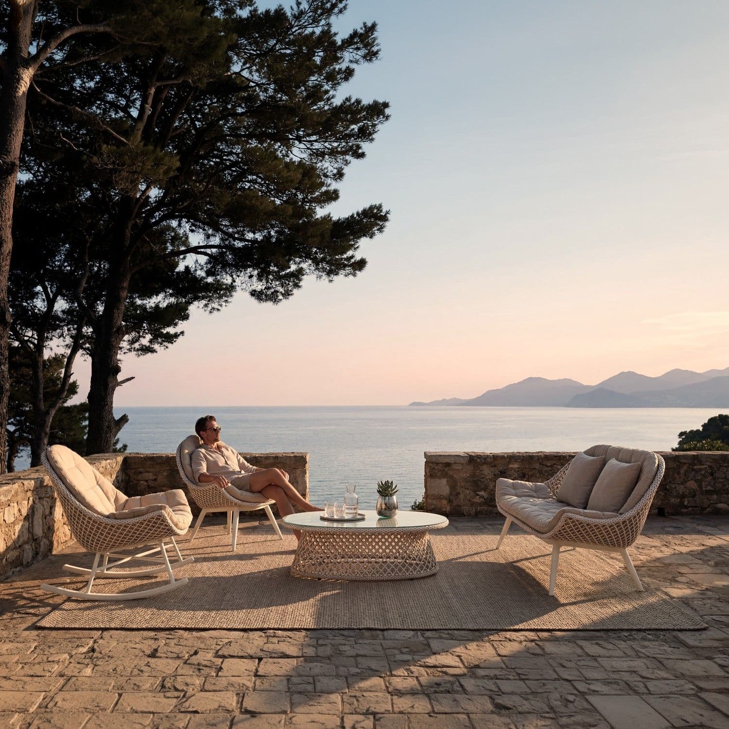 BLOOM Muse luxury outdoor lounge set: rocking chair, lounge chair, coffee table. Handcrafted woven design on a coastal terrac